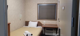 A lodge room furnished with a bed, desk, dresser, TV and air conditioner unit